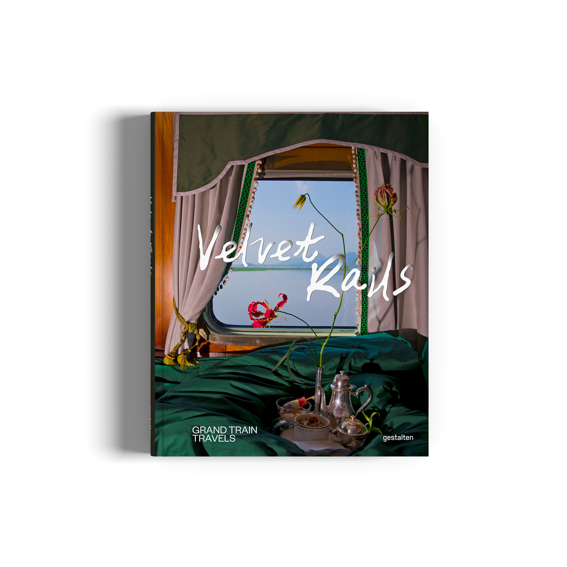 A hardcover book titled 'Velvet Rails', featuring a dark green velvet interior with a window, flowers, and a silver carafe on the cover,.