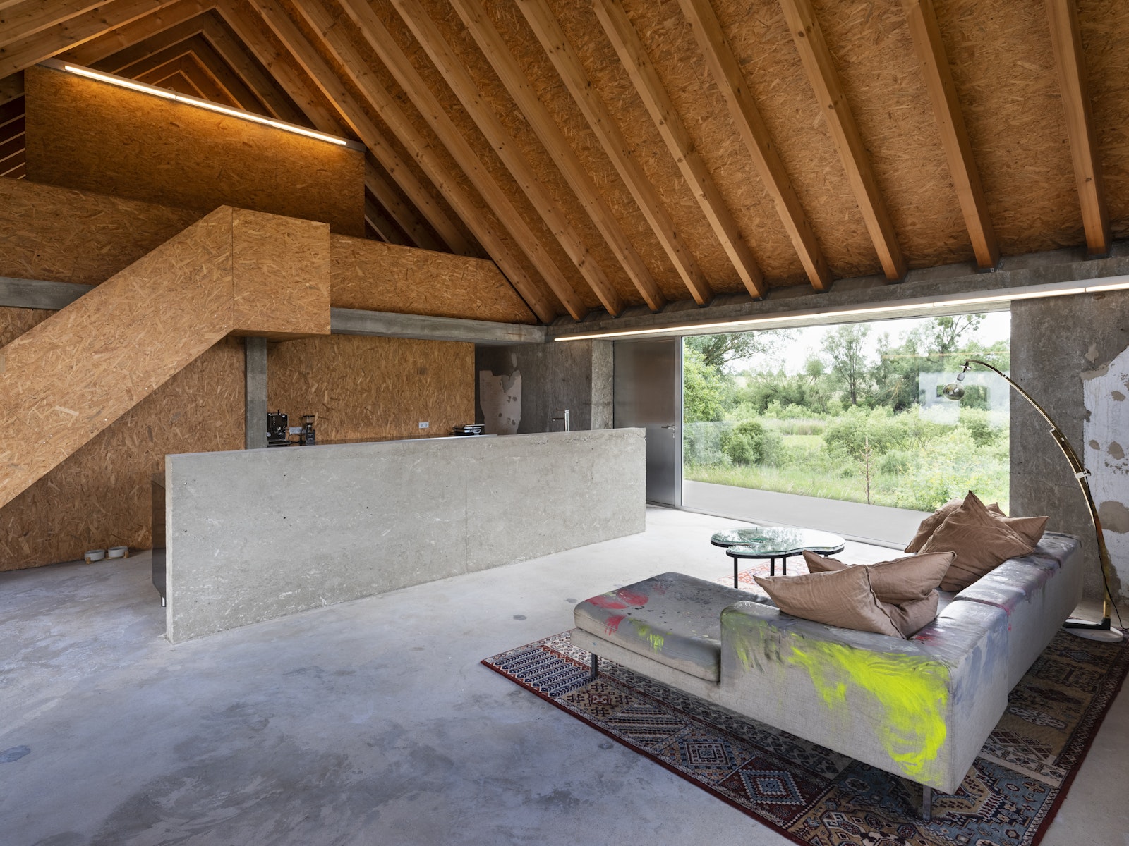 Modern living room with wooden ceiling and concrete walls.